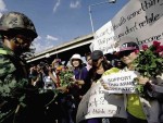 A THAI soldier (left) receives roses from activists to show support for the Thai military at the Army Club in Bangkok on May 23. Thailand’s Army said 155 prominent figures, including ousted government leaders, were banned from leaving the country without permission following a military coup. AFP