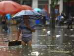 In this Tuesday, July 15, 2014 photo, a Chinese man holds an umbrella while wading through a flooded street in Changsha in south China's Hunan province. AP
