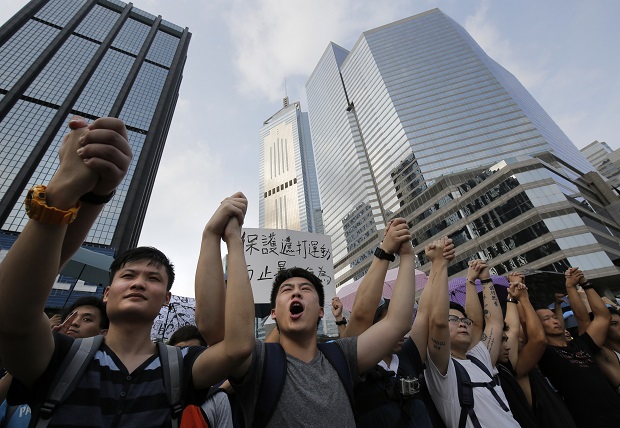 Protesters shout slogans outside a flag-raising ceremony where Hong Kong's embattled leader attended in Hong Kong, Wednesday, Oct. 1, 2014, to mark China's National Day. Hong Kong Chief Executive Leung Chun-ying attended the flag-raising ceremony Wednesday to mark China's National Day after refusing to meet pro-democracy demonstrators despite their threats to expand the street protests that have posed the stiffest challenge to Beijing's authority since China took control of the former British colony in 1997. (AP Photo/Vincent Yu)