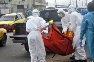 Health workers in protective gear carry the body of a person suspected to have died from Ebola on the street of Monrovia, Liberia. AP