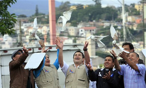 Honduras President Juan Orlando Hernandez, center, and his wife, Ana Garcia Carias, second from left, release white doves with other unidentified people during a march with thousands of people participating, in downtown Tegucigalpa, Honduras, Saturday, Nov. 29, 2014. The government organized march calling for a peaceful Christmas. Plagued by gang violence, Honduras has one of the highest murder rates in the western hemisphere. AP