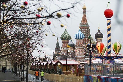 Municipal workers walk along a fence surrounding a Christmas market at Red Square with St. Basil's Cathedral in the background in Moscow, Russia, Tuesday, Dec. 9, 2014.  AP