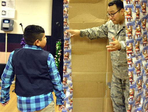 U.S. Air Force Sgt. Jose Hernandez surprizes his son Isaiah after waiting in a card board box adorned with wrapping paper Thursday morning, Dec. 18, 2014, at R.L. Martin Elementary in Brownsville, Texas. Hernandez returned early from a tour in South Korea to spend Christmas with his family. AP