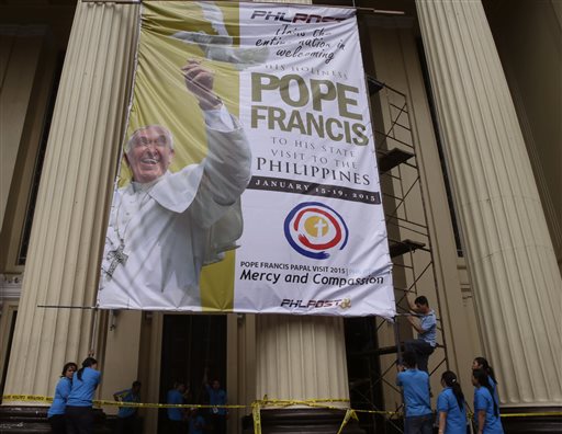 Philippine postal employees help install a huge tarpaulin heralding this week's pastoral visit of Pope Francis at the post office building Monday, Jan. 12, 2015 in Manila, Philippines. AP