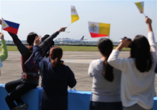 Filipinos wave flags of the Philippines and Vatican as the plane carrying Pope Francis prepares to take off at Villamor Air Base in Pasay City on Monday, Jan. 19, 2015. AP PHOTO/AARON FAVILA