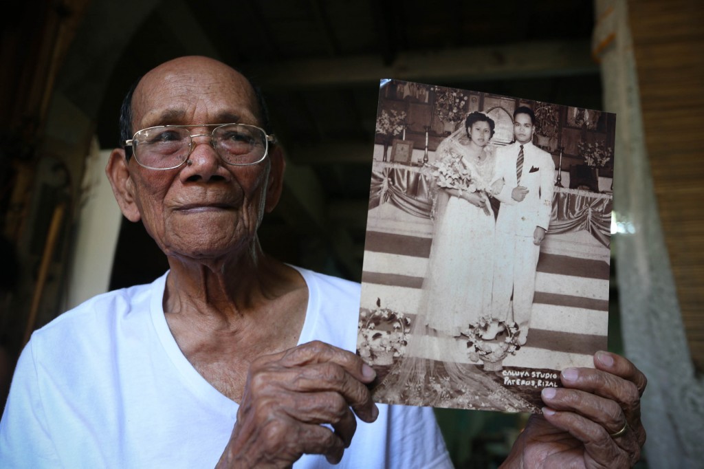 100 year old World War II veteran Jose Santiago Quilatan Sr. showing a black-and-white photo of his wedding day with his young bride Lourdes Dimaguila, then 20 years old and he at 26.  INQUIRER PHOTO/LYN RILLON