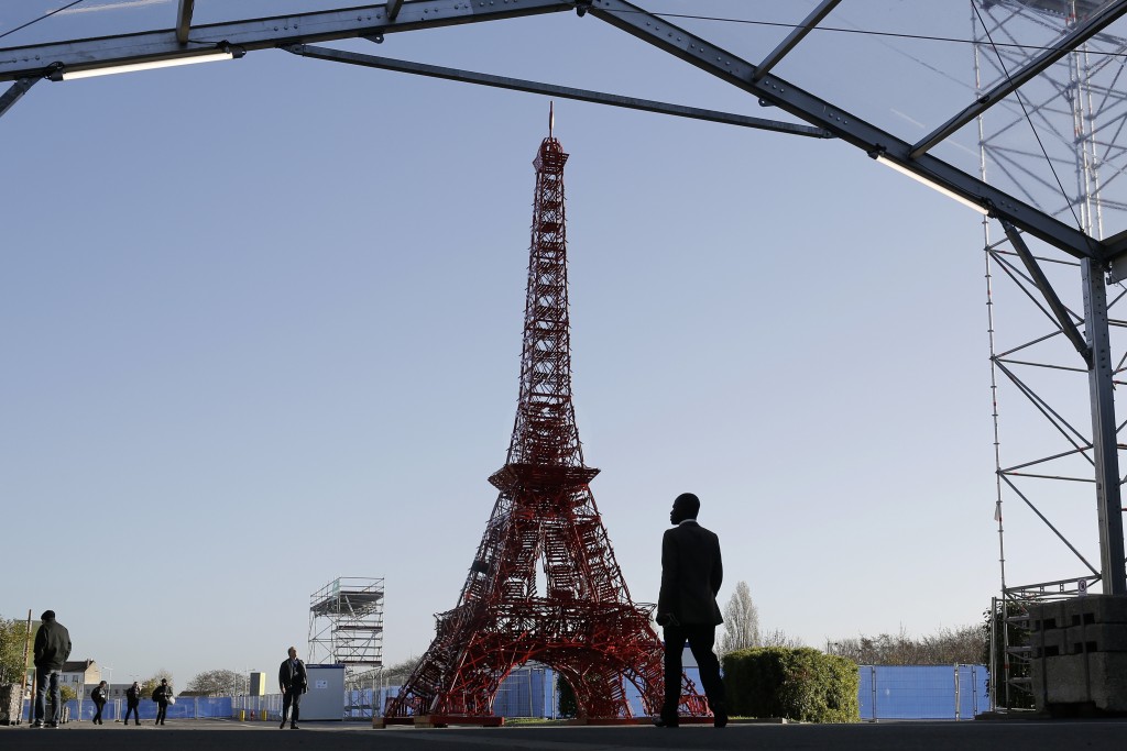 People walk in front of a reproduction of the Eiffel tower at the United Nations Climate Change Conference in Le Bourget, outside Paris, Saturday, Nov. 28, 2015. The site of Paris-Le Bourget will officially become United Nations territory for the COP 21 conference which is scheduled to start on Nov. 30. (AP Photo/Laurent Cipriani)