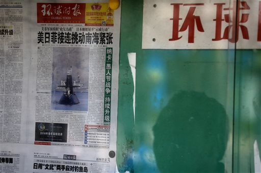 A Chinese man is reflected on a glass as he reads China's nationalistic tabloid Global Times' front page article with a headline that reads: "the U.S., Philippine and Japanese military steer tension in the disputed South China Sea" posted on a public newspaper bulletin board in Beijing, Tuesday, April 5, 2016. Thousands of U.S. and Philippine troops, along with Australian defense forces, began annual drills Monday to prepare to quickly respond to a range of potential crises, including in the disputed South China Sea. The exercises have been opposed in recent years by China, which has territorial disputes in the South China Sea with several countries, including the Philippines, and suspects the drills are part of efforts to contain Beijing. Washington and Manila say the drills are not directed against China, and that they also focus on responding to natural disasters and humanitarian crises. (AP Photo/Andy Wong)