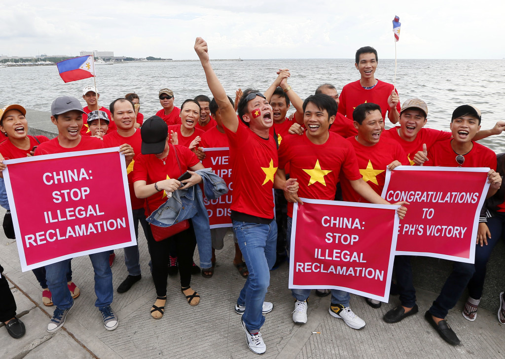 Vietnamese expatriates cheer while displaying placards during a rally by the Manila's baywalk before the Hague-based U.N. international arbitration tribunal is to announce its ruling on South China Sea Tuesday, July 12, 2016, Philippines. The Vietnamese are supporting the Philippines' case it filed before the international tribunal on China's nine-dash line claim in the South China Sea. (AP Photo/Bullit Marquez)