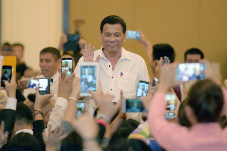 Philippine President Rodrigo Duterte greets members of the Filipino community as he arrives in the Cambodian capital Phnom Penh on December 13, 2016.  Duterte is on a two-day state visit to Cambodia. / AFP PHOTO / TANG CHHIN SOTHY