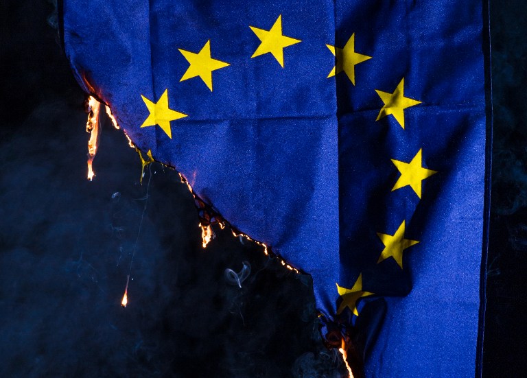 A photo-illustration shows a European Union (EU) flag as it burns near Manchester, northern England on March 25, 2017, ahead of the British government's planned triggering of Article 50 tomorrow. British Prime Minister Theresa May will send a letter to EU President Donald Tusk with Britain's formal departure notification on Wednesday, opening up a two-year negotiating window before Britain actually leaves the bloc in 2019. / AFP PHOTO / Oli SCARFF