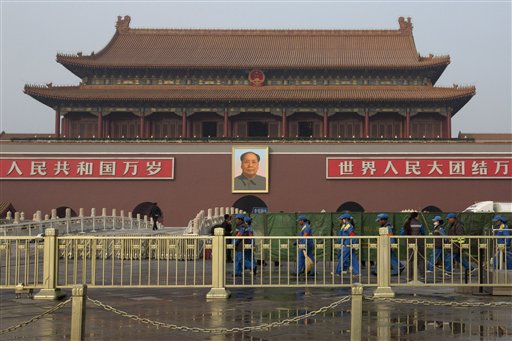 Traffic policemen walk past plainclothes policemen place green net shields in front of Tiananmen Gate in Beijing. AP 