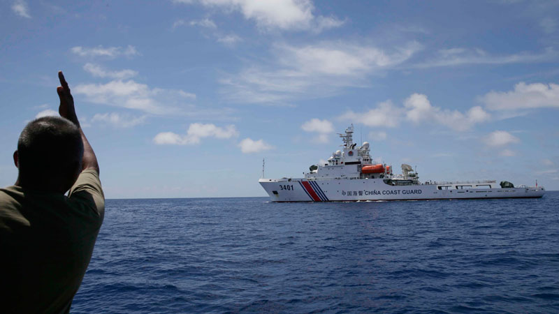 A Philippine Marine gestures at a Chinese Coast Guard vessel which tries to block a Philippine Government vessel AM700 from approaching the Second Thomas Shoal (local name Ayungin Shoal) to resupply and replace fellow marines who were deployed for almost five months Saturday, March 29, 2014 off South China Sea on the West Philippine Sea. On April 9, Filipino fishermen said, a Chinese vessel used water cannon to drive away at least 80 fishermen from Panatag Shoal (Scarborough Shoal). AP FILE PHOTO