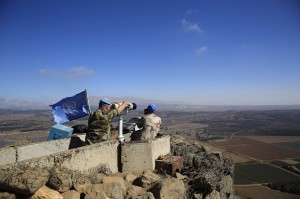 In this photo taken on Tuesday, Sept. 16, 2014, U.N. peacekeepers from the United Nations Disengagement Observer Force, also known as UNDOF, observe Syria's Quneitra province at an observation point on Mt. Bental in the Israeli-controlled Golan Heights, overlooking the border with Syria. For four decades, a multinational United Nations mission has quietly monitored the sleepy Golan Heights — providing a symbol of stability between bitter enemies as it enforced a truce between Israel and Syria. But as Syria has plunged into civil war and the peacekeepers themselves have become targets of al-Qaida-linked rebels, the U.N. observer force has begun to fall apart, leaving its future — and the prospects for ever establishing peace in this rugged area of the Middle East — in doubt.(AP Photo/Tsafrir Abayov)