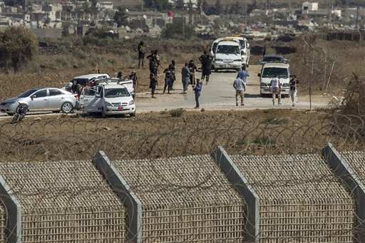 Al-Qaida-linked Syrian militants gather around vehicles carrying UN peacekeepers from Fiji before releasing them, as they arrive near the Syrian village of Al Rafeed in Syrian-controlled side of the Golan Heights, seen from the border of the Israeli side Thursday, Sept. 11, 2014. Hundreds of UN troops withdrew from the Syrian to the Israeli-occupied sector of the Golan on Monday, an AFP correspondent said, two weeks after Al-Qaeda-linked rebels kidnapped dozens of peacekeepers.  AP PHOTO/GIL ELIYAHU