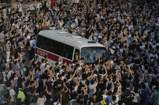 A police car is blocked by protesters after thousands of people block a main road to the financial central district outside the government headquarters in Hong Kong, Sunday, Sept. 28, 2014. AP