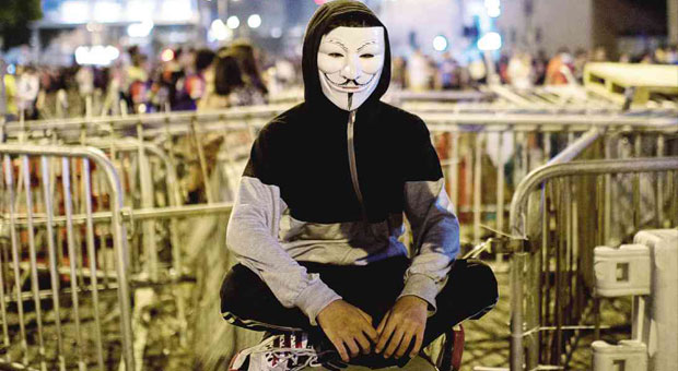 GUY FAWKES MASK  A prodemocracy protester wearing a Guy Fawkes mask sits near barricades blocking a road in the central district of Hong Kong, where Filipino domestic workers congregate on their days off.  AFP