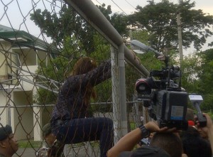 Marilou Laude climbs over the gate leading to the detention facilities inside the Mutual Defense Board-Security Engagement Board at Camp Aguinaldo.
