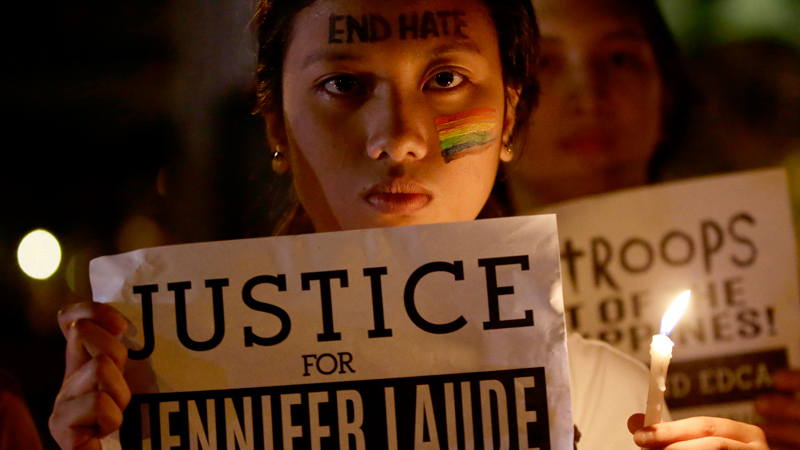 Protesters, mostly supporters of LGBT (Lesbians, Gays, Bisexuals and Transgenders), hold a lit candle and display messages to demand justice in the killing of a Filipino transgender Jeffrey "Jennifer" Laude, with a U.S. Marine as a possible suspect Tuesday, Oct. 14, 2014 in Manila, Philippines. Dozens of activists burned a mock U.S. flag as they protested at the U.S. Embassy in Manila on Tuesday, demanding that Washington hand over to the Philippines a U.S. Marine suspected in the killing of a transgender Filipino that the demonstrators labeled a hate crime. (AP Photo/Bullit Marquez)