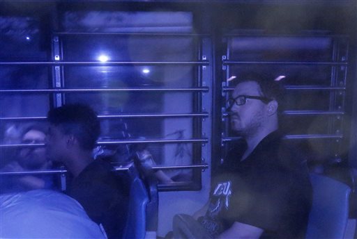 Rurik George Caton Jutting, 29, right, is escorted by police officers in an police van after his appearing in a court  in Hong Kong Monday, Nov. 3, 2014.  AP