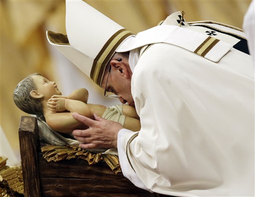 Pope Francis kisses a statue of Baby Jesus as he celebrates the Christmas Eve Mass in St. Peter's Basilica at the Vatican, Wednesday, Dec. 24, 2014. AP