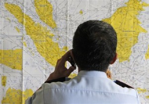 An airport official checks a map of Indonesia at the crisis center set up by local authority for the missing AirAsia flight QZ8501, at Juanda International Airport in Surabaya, East Java, Indonesia, Sunday, Dec. 28, 2014. The AirAsia plane with over 160 people on board lost contact with ground control on Sunday while flying over the Java Sea after taking off from the provincial city in Indonesia for Singapore. (AP Photo/Trisnadi)