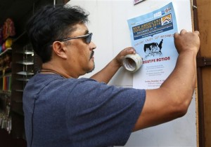 This Dec. 10, 2014 photo shows Tony Bernabe posts a flier in downtown Los Angeles advertising a massive information session scheduled for this weekend to tell immigrants more about President Barack Obama’s executive actions on immigration. Immigrant advocates have been holding workshops in churches, schools and meeting rooms across the country to dispel rumors, ward off fraud and help immigrants here illegally determine if they qualify to apply for a work permit and protection from deportation. (AP Photo/Nick Ut)