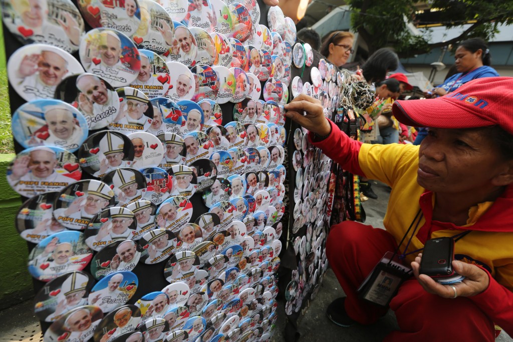 a woaman buying Pope Frnacis pins along Quirino Avenue in Manila. INQUIRER PHOTO/JOAN BONDOC