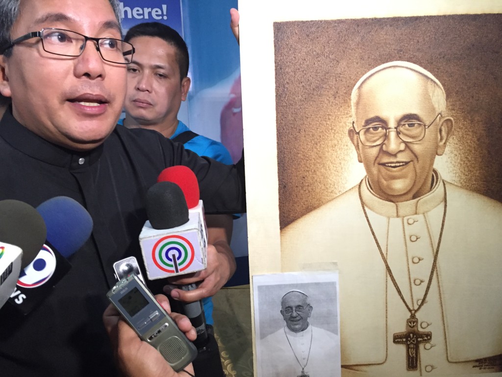 Fr. Anton Pascual presents a wood burning portrait of Pope Francis created by an inmate of the New Bilibid Prison. Photo by Kristine Angeli Sabillo/INQUIRER.net