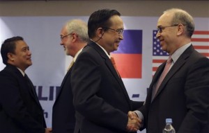 US Assistant Secretary of State Daniel Russel, right, shakes hands with Philippine Undersecretary of Foreign Affairs Evan P. Garcia, second from right, after their press conference on the fifth Philippines-United States Bilateral Strategic Dialogue in Manila, Philippines Wednesday, Jan. 21, 2015. Garcia said surveillance photographs have shown that China's reclamation of contested reefs in the South China China has assumed a "massive" scale, with Beijing continuing its expansion in disputed territories despite past protests. (AP Photo/Aaron Favila)