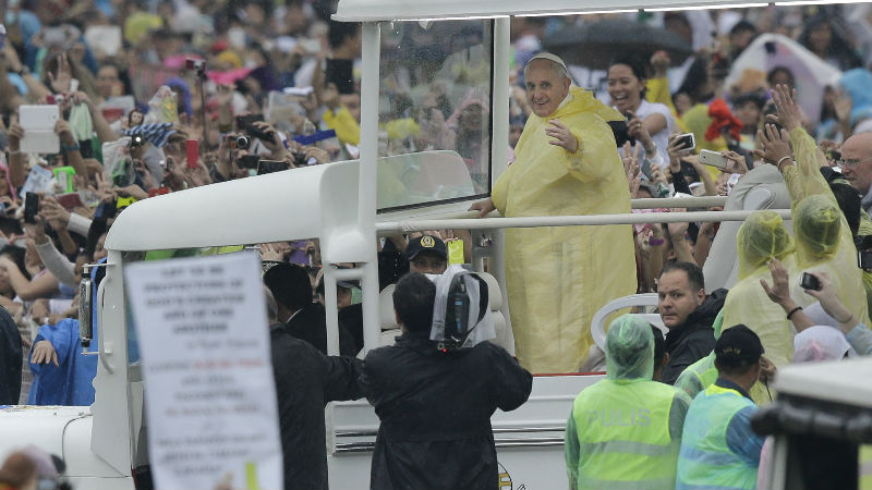 Pope Francis waves to the faithful as he arrives at Rizal Park to celebrate his final Mass in Manila, Philippines, Sunday, Jan. 18, 2015. Millions filled Manila's main park and surrounding areas for Pope Francis' final Mass in the Philippines on Sunday, braving a steady rain to hear the pontiff's message of hope and consolation for the Southeast Asian country's most downtrodden and destitute. (AP Photo/Bullit Marquez)