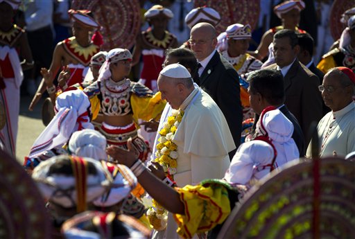 Pope Francis walks upon arrival as colorful Sri Lankan dancers perform in Colombo, Sri Lanka, Tuesday, Jan. 13, 2015. Pope Francis has arrived safely in Sri Lanka for the first leg of a weeklong trip to Asia, received at the airport by newly elected President Maithripala Sirisena and Cardinal Malcolm Ranjith. AP