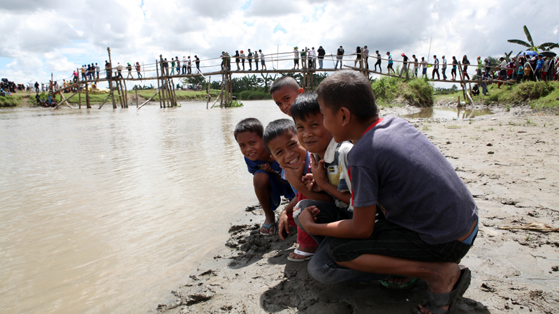 BACK TO LIFE ANEW  Children chat on the riverbank as residents of Tukanalipao village cross a wooden bridge in Mamasapano, Maguindanao province, where 44 police commandos, 18 Moro rebels and five civilians were killed during intense fighting that stalled peace talks.  JEOFFREY MAITEM/INQUIRER MINDANAO
