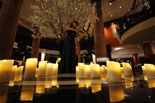 Eriko Ukimura plays the violin during the "Earth Hour" in Tokyo Saturday, March 28, 2015. The light at a Tokyo hotel lobby was turned off momentarily on Saturday as part of global campaign to raise awareness on environmental issues. AP