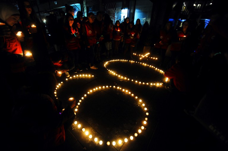 Activists of the Red Cross light candles to form the number "60" during "Earth Hour" in Skopje's main square on March 28, 2015. Thousands of cities around the world turned off lights on emblematic buildings during the "Earth Hour", a global event to warn of the dangers of climate change. AFP 