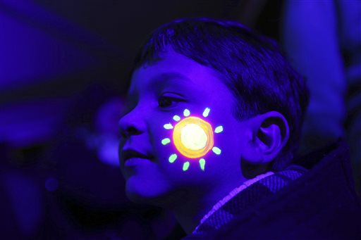 A boy with his face decorated with luminous ink poses for a photograph with others during the symbolic switching off of the lights known as Earth Hour, Saturday, March 28, 2015, in Lisbon, Portugal. At 8:30 p.m. local time, individuals, businesses, cities and landmarks around the world switched off their lights for one hour to focus attention on climate change. AP