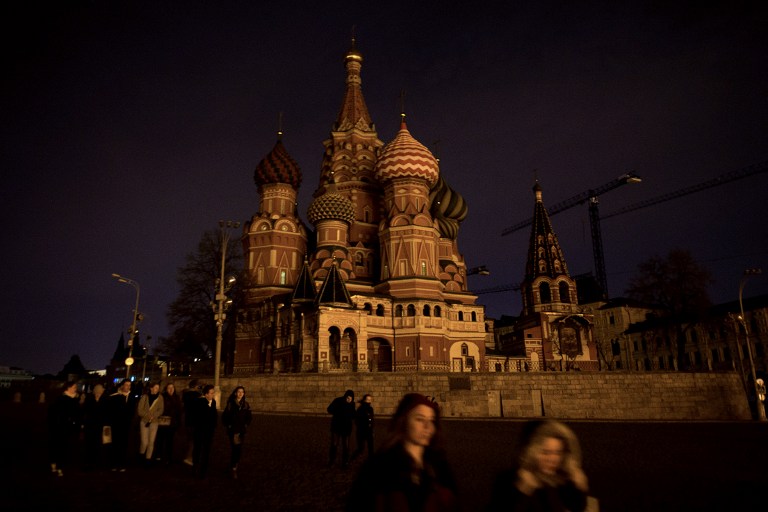 People walk past St. Basil's Cathedral with its lights off as part of the Earth Hour environmental campaign in central Moscow on March 28, 2015. AFP 