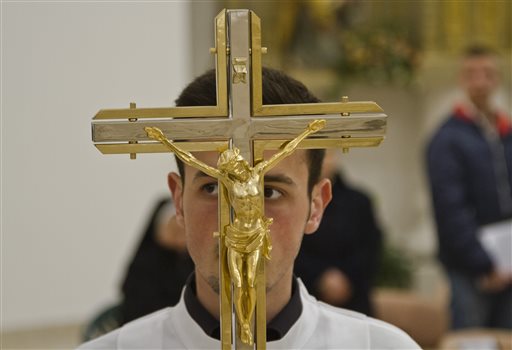 A crucifix is held by a young priest during the Easter Vigil mass at Mother Teresa Cathedral in Kosovo capital Pristina Saturday, April 4, 2015 as Catholics prepare for Easter Sunday, the most important religious holiday for the worshippers. AP