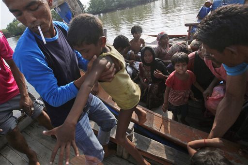 An Acehnese fisherman helps to carry a young boy as boats full of rescued migrants arrive in Simpang Tiga, Aceh province, Indonesia Wednesday, May 20, 2015. The Philippines won praise from international organizations for declaring its willingness to give asylum to the unwanted Rohingya refugees from Bangladesh and Burma (Myanmar) who are now stranded in the Andaman Sea and the Straits of Malacca. AP PHOTO/BINSAR BAKKARA 