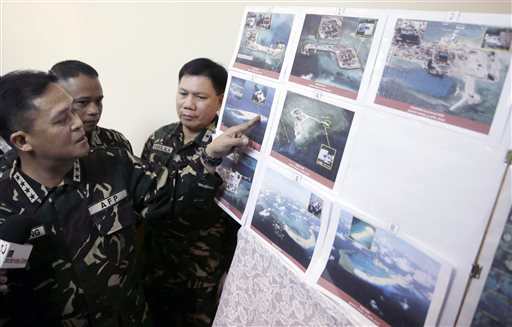 In this April 20, 2015, file photo, Armed Forces of the Philippines Chief of Staff Gen. Gregorio Pio Catapang, left, points to reveal recent images of China's reclamation activities being done at the disputed islands in the South China Sea during a news conference at Camp Aguinaldo at suburban Quezon City. The Philippines expressed alarm Thursday, May 7, over what it said were escalating Chinese efforts to drive off Filipino aircraft from a disputed South China Sea island garrisoned by Manila, in dangerous confrontations.  AP PHOTO/BULLIT MARQUEZ 