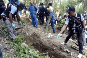 In this May 2, 2015 file photo, Thai police officials measure a shallow grave in Padang Besar, Songkhla province, southern Thailand. Malaysian authorities said Sunday, May 24 that they have discovered graves in more than a dozen abandoned camps used by human traffickers on the border with Thailand where Rohingya Muslims fleeing Myanmar have been held.  AP Photo