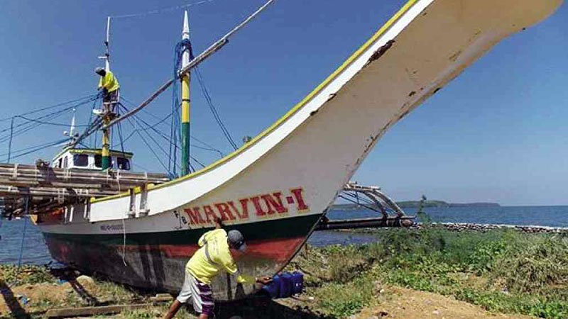 FOR SALE  Fishermen Silver Lopez and Raymart de Claro remove old paint and scratches, scrape off patches of barnacles on the 9-meter fishing boat Marvin-I. The vessel is up for sale since its owner has abandoned the idea of going back to the disputed Panatag Shoal in the West Philippine Sea.  ALLAN MACATUNO/INQUIRER CENTRAL LUZON
