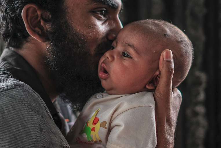A Rohingya man holding his daughter while waiting near the United Nations High Commissioner for Refugees (UNHCR) office in Kuala Lumpur in August. A rumour about refugee status cards being issued by the UNHCR saw hundreds of Rohingya refugees throng the office, local media reported.PHOTO: AGENCE FRANCE-PRESSE
