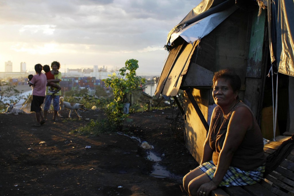 In this Monday, Nov. 16, 2015 photo, Juanita Espinosa sits and enjoys a sunset in front of her house in the slum "Smokey Mountain" in Manila, Philippines. Just a few miles from the gleaming venue hosting President Barack Obama and other world leaders sits Manila's slum of slums on a mountain of trash, a potent reminder of the dilemmas that haunt the free trade and globalization agenda promoted by groups like the Asia-Pacific Economic Cooperation forum. (AP Photo/Lino Escandor II)