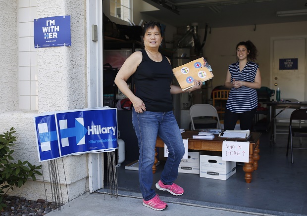 In this Feb. 12, 2016, photo, Cynthia Ameli, center, a Chinese-American, picks up materials from Sarah Gibson before heading out to canvass for presidential candidate Hillary Clinton in Las Vegas. Asian-American voters are the fastest-growing racial group in the U.S. and both parties increasingly are wooing them. (AP Photo/John Locher)