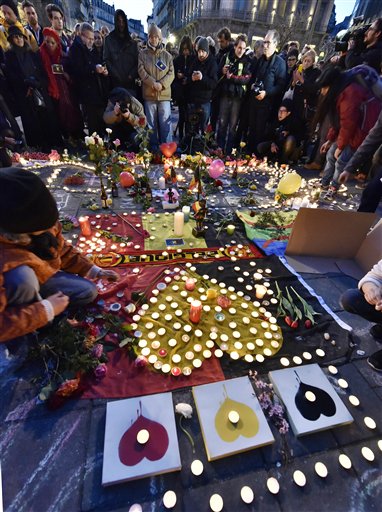 People put candles on painted hearts with the Belgian colors to mourn for the victims at the place de la Bourse in the center of Brussels, Tuesday, March 22, 2016. Bombs exploded at the Brussels airport and one of the city's metro stations Tuesday, killing and wounding scores of people, as a European capital was again locked down amid heightened security threats. (AP Photo/Martin Meissner)