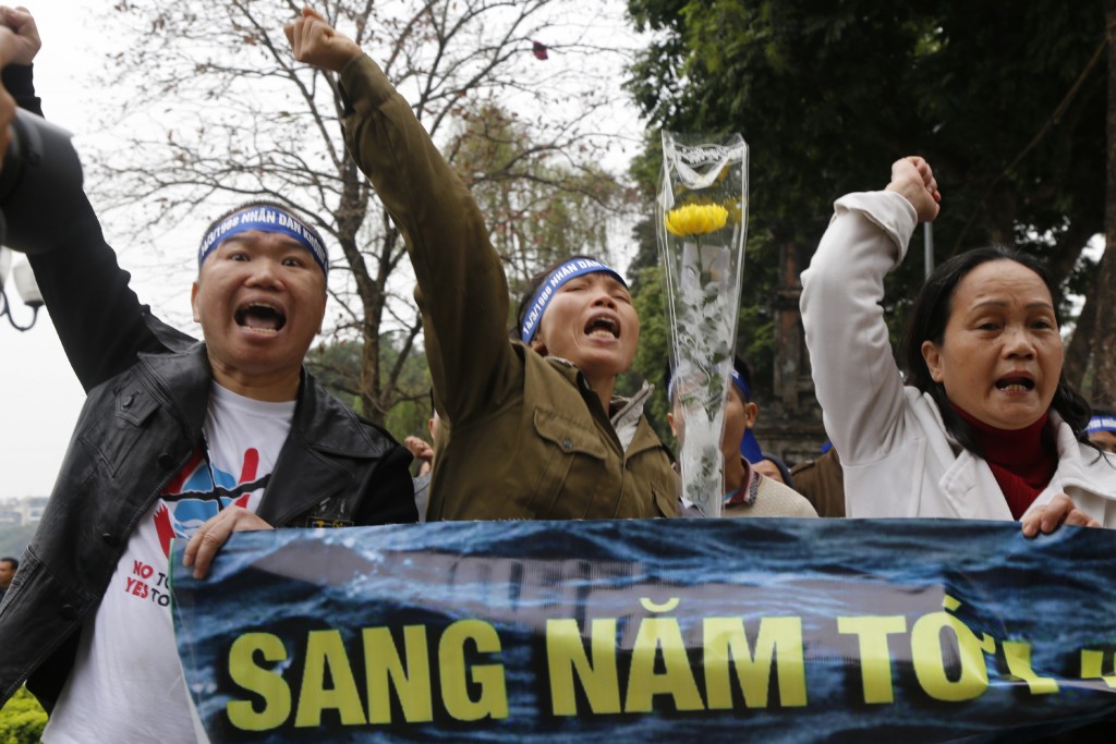 Vietnamese shout anti-China slogans during a protest in Hanoi, Vietnam Monday, March, 14, 2016 as about 200 Vietnamese gather to remember 64 Vietnamese soldiers who were killed by the Chinese navy in a clash 28 years ago in the disputed South China Sea. They lit incense and laid flowers at the statue of King Ly Thai To, a Vietnamese hero, and then marched around the landmark Hoan Kiem Lake, chanting "down with Communist China's aggression" in the commemoration that lasted an hour. (AP Photo/Tran Van Minh)