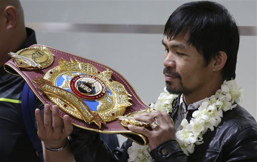 Filipino boxer and Congressman Manny Pacquiao looks at his WBO championship belt smiles as he arrives at the Ninoy Aquino International Airport in suburban Pasay city, south of Manila, Philippines, Thursday, April 14, 2016. Pacquiao beat American Timothy Bradley during their WBO welterweight title boxing match in Las Vegas. He is running for the senate in the elections next month. (AP Photo/Aaron Favila)