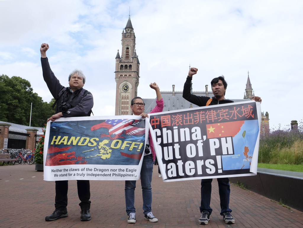 Protesters stand outside the Peace Palace in The Hague, Netherlands, on Tuesday, July 12, 2016, ahead of a ruling by the Permanent Court of Arbitration (PCA) on the dispute between China and the Philippines over the South China Sea. China has intensified the drumbeat of its opposition to an international tribunal's ruling expected Tuesday that could threaten its expansive claims in the South China Sea. AP PHOTO