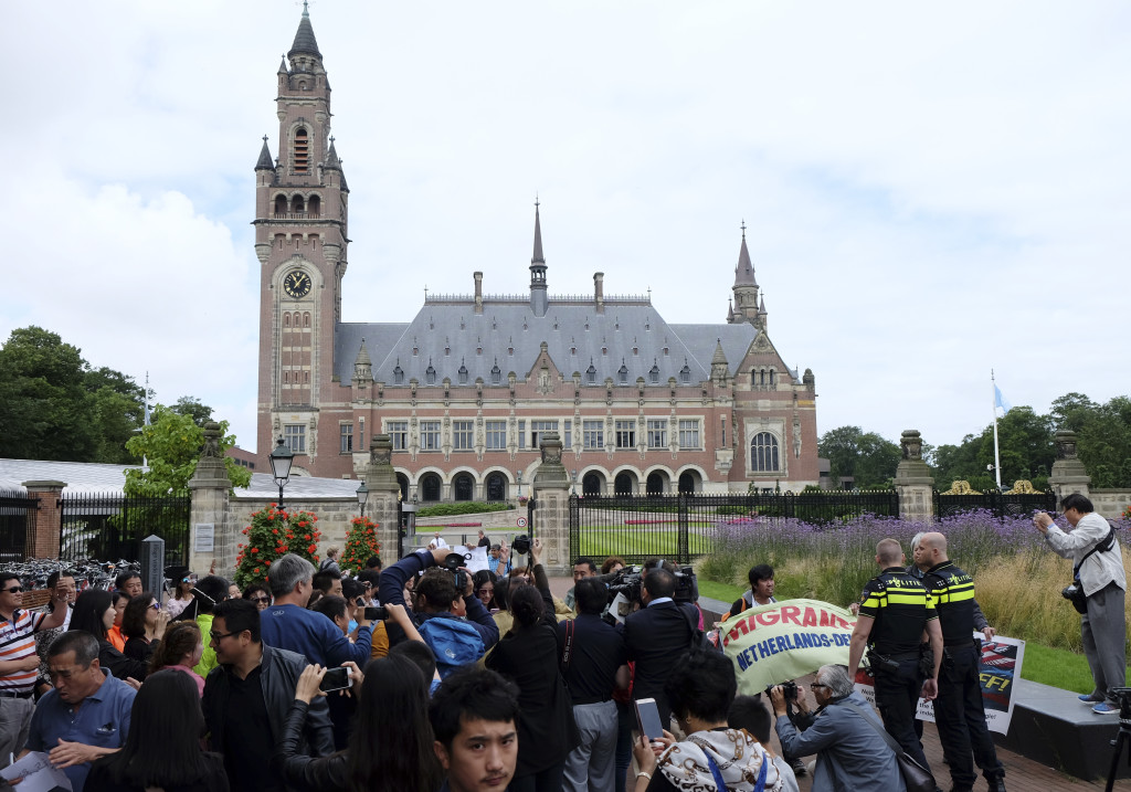 Demonstrators, police, and media gather outside the Peace Palace in The Hague, Netherlands, on Tuesday, July 12, 2016, ahead of a ruling by the Permanent Court of Arbitration (PCA) on the dispute between China and the Philippines over the South China Sea. China has intensified the drumbeat of its opposition to an international tribunal's ruling expected Tuesday that could threaten its expansive claims in the South China Sea. (AP Photo/Mike Corder)